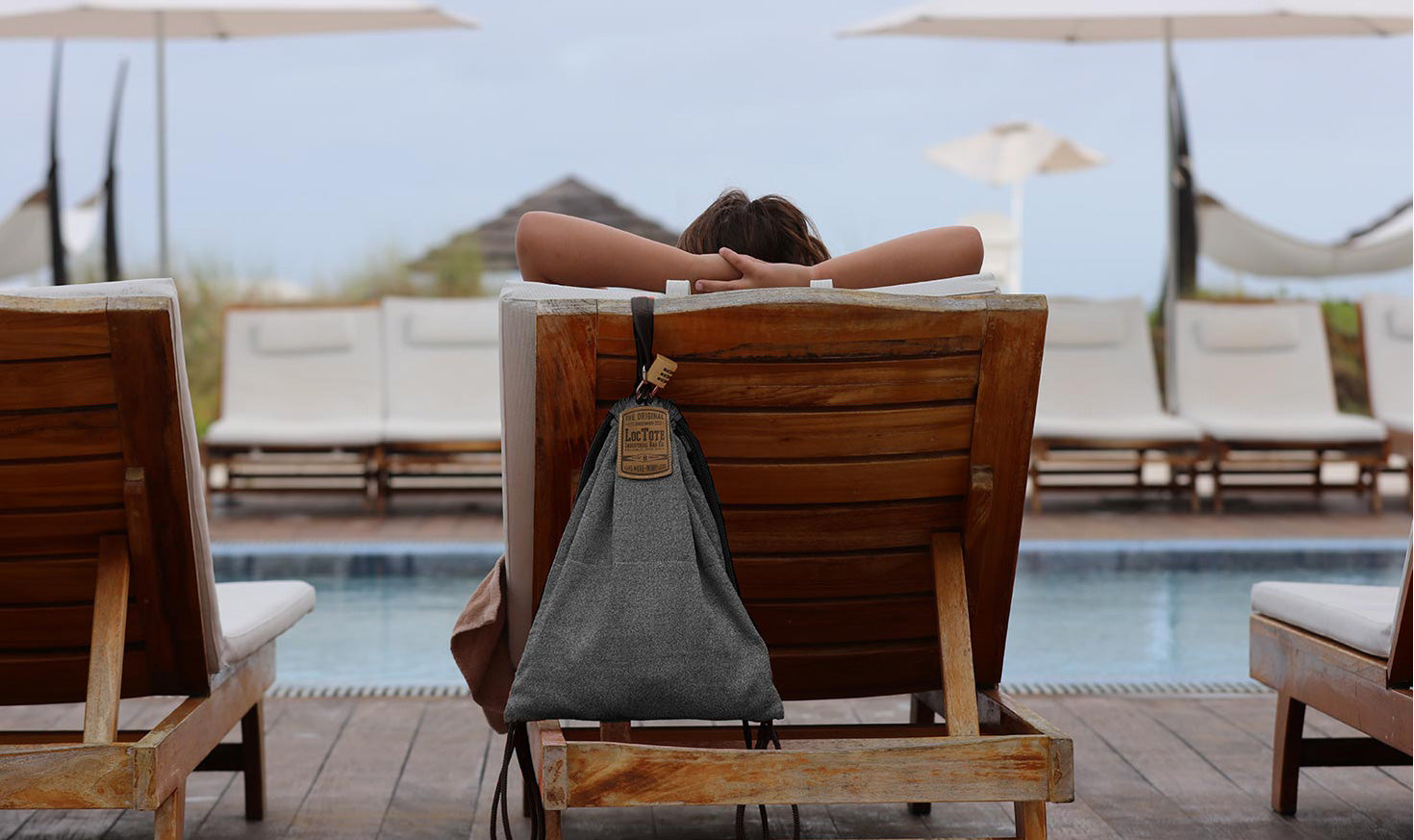 A woman laying next to the pool with a loctote bag