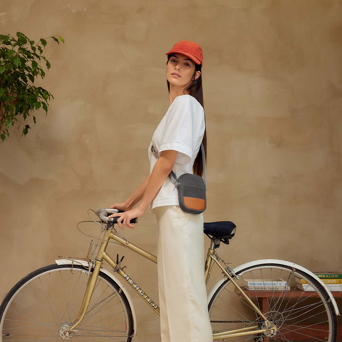 Woman wearing a white t-shirt, beige slacks, a bright orange hat and Loctote's Neck Pouch in Vintage Grey 